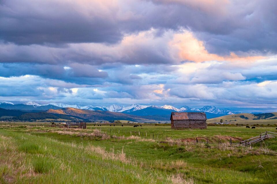 A red barn on open pasture under evening cloud