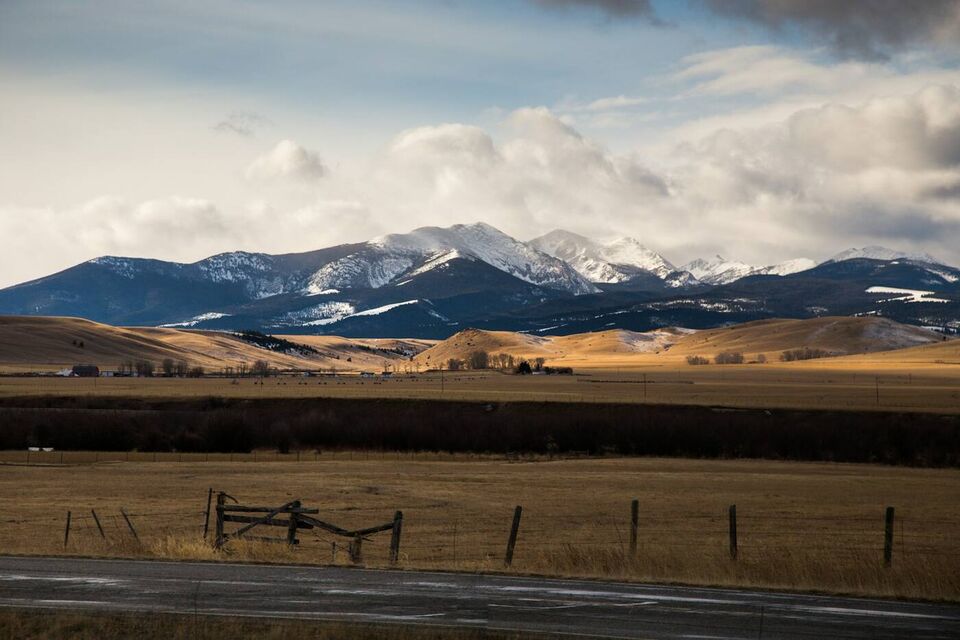 A buck-and-rail fence along a wintering field below the mountains